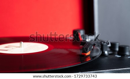 Vinyl needle stylus on rotating black vinyl plate with copy space. Turntable vinyl record player on red background