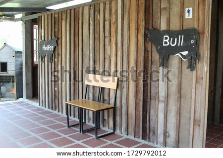 Cow-shaped toilet sign, made of black painted wood.