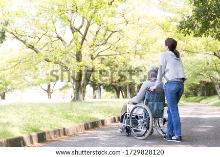 Rear view of elderly man in wheelchair and care helper Royalty-Free Stock Photo #1729828120