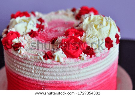 
cake decorated with cream cheese with red and white roses on a soft background
