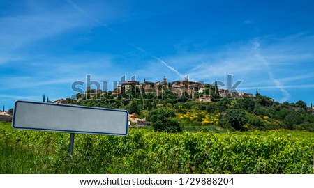 Outside sign against blue sky, green vineyards and medievel town. Incredibly scenic drive through the southern Cotes-du-Rhone Villages. Road sign with a blank signpost for your text.