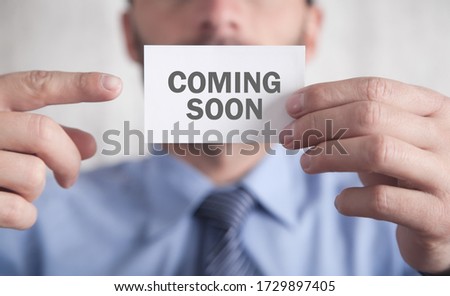 Businessman showing Coming Soon text on business card.