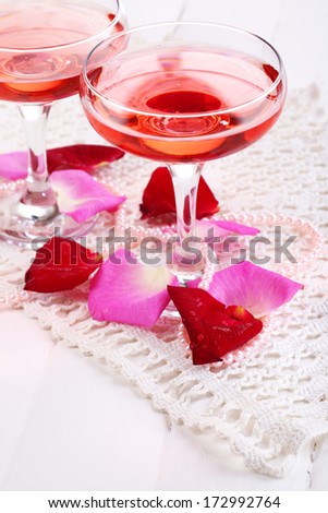 Composition with pink sparkle wine in glasses and rose petals isolated on white