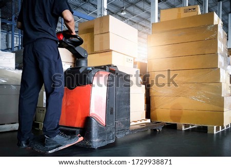 Interior of storage warehouse, Worker with electric forklift pallet jack unloading pallet goods, package boxes, warehouse shipping delivery logistic and transport. Royalty-Free Stock Photo #1729938871