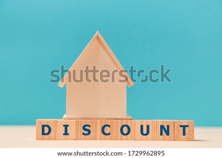 Mortgage. Real estate. Discount on property. Wooden house miniature standing on cubes with letters on blue. Copy space