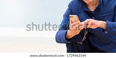 senior man using mobile phone on the beach