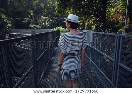 Woman in dress and hat standing alone on Canopy walkway at Queen Sirikit Botanic Gardens in Chiang Mai, Thailand, Walkway in the middle of the forest