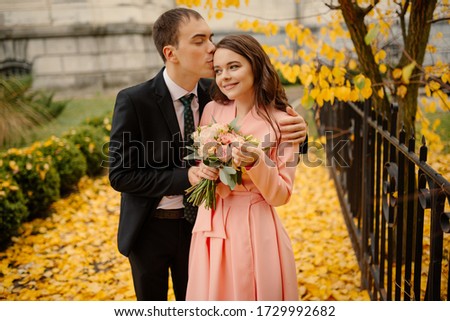 Newlyweds groom and bride walking in autumn park near vintage atmosphere gothic cathedral. Wedding, love concept.