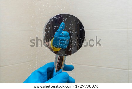shower watering can in hands with rubber gloves. cleaning the bathroom and cleaning the shower cabin. reflection of a hand making a kind gesture. concept of good and high-quality work. copy space.