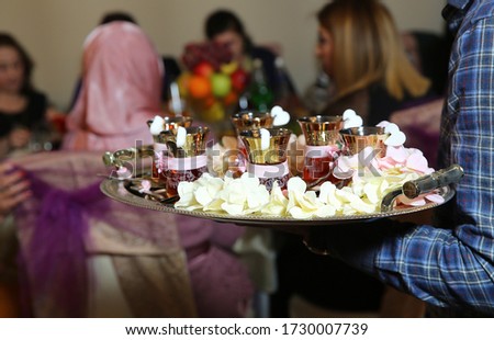 tea in eastern armudu glass on the silver salver on the white tablecloth, Arabic, Turkish, Azerbaijani customs . armudu cups . Armudu cups for the engagement ceremony . Boy holding silver salver