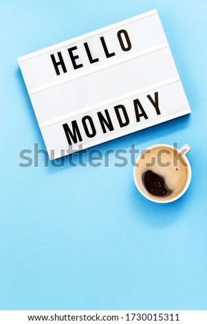 Text "hello monday" on lightbox and cup of coffee for holiday - Thank God It's Monday. Start of working week concept. Top view on blue background.