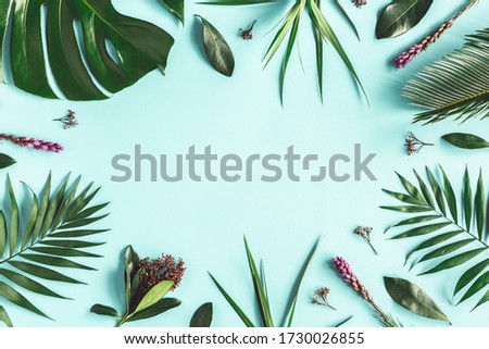 Summer composition. Tropical flowers and leaves on blue background. Summer concept. Flat lay, top view, copy space