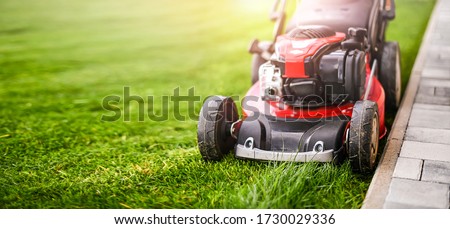 Lawn mover on green grass in modern garden. Machine for cutting lawns. Royalty-Free Stock Photo #1730029336