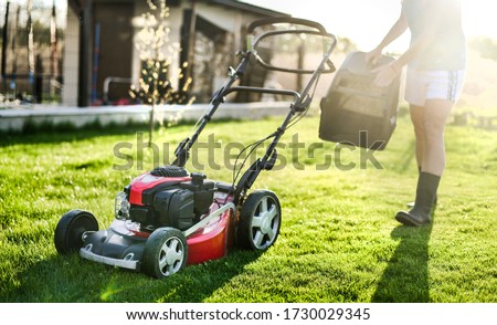 Lawn mover on green grass in modern garden. Machine for cutting lawns. Royalty-Free Stock Photo #1730029345