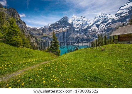 Amazing tourquise Oeschinnensee with waterfalls, wooden chalet and Swiss Alps, Berner Oberland, Switzerland. Royalty-Free Stock Photo #1730032522