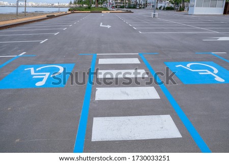 Disabled parking divided by a pedestrian crossing on the beach. Empty convenient parking for cars during a pandemic Covid-19 in Europe. Parking on the beach. Marking on asphalt road.