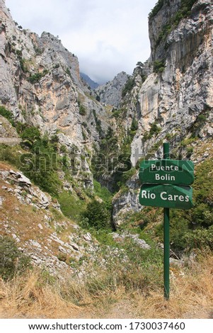 river name sign and point of intrest at the entrance of a rugged mountain hiking path through a steep gorge and along a fast flowing river