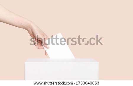 Civilized Equal Rights Concept. Female Hand Lowers Ballot In Ballot Box On Light Suntan Peach Background Royalty-Free Stock Photo #1730040853