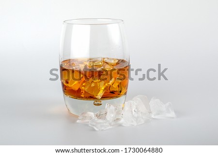 Glass of whisky and ice cubes on white background. Alcohol, addiction and entertainment concept