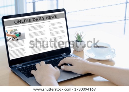 Cropped image of businessman reading news on laptop at office desk