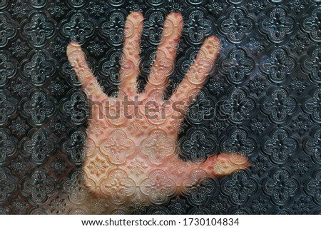 hand behind glass with patterns