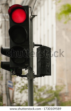 Black plastic traffic light hangs on the support, it burns a red prohibitive signal of the road crossing