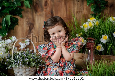 Little girl in light spring dress, in the studio, decorated with spring decoration flowers in pots and greens, summer, green, fresh