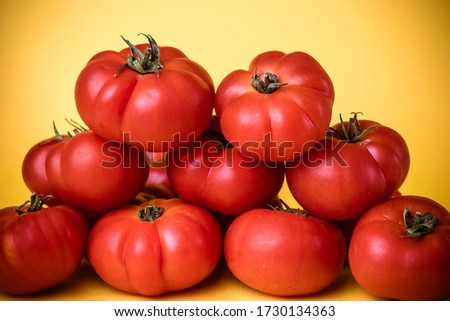 Group of tomatoes in pyramid with yellow background.