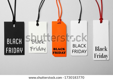 Different tags with text BLACK FRIDAY on light background, flat lay