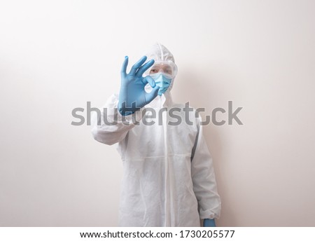 Male medical doctor with ok sign. Doctor in protective suit, ready to fight against the virus 