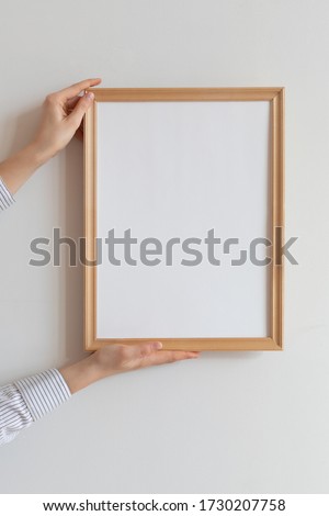 Cropped hand of woman holding picture frame against wall. Frame mockup.  Royalty-Free Stock Photo #1730207758