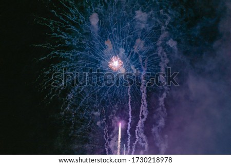 Blue and yellow fireworks with smoke over the black sky. Low key exposure. Selective focus.