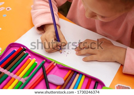 little girl drawing with colored pencils on paper