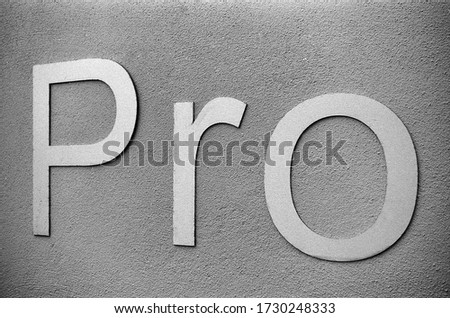 the word pro, consisting of three letters on a wall, this black and white photo was taken with a pinhole film camera, which corresponds to the camera characteristic
