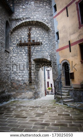 Unique wooden cross on the wall in the medieval town. (Annot, Alpes de Haute Provence, France). Shadowed angles.