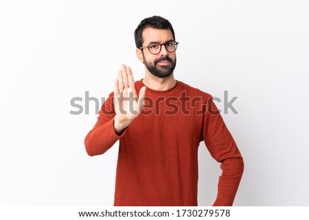Caucasian handsome man with beard over isolated white background making stop gesture
