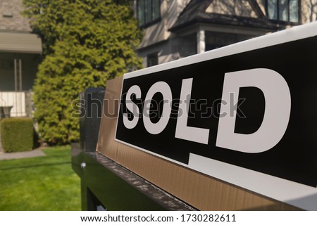 Sign sold in front of a detached house in residential area. Real estate bubble, new listings, hot housing market, overpaid, overpriced property, buyer activity, spring and summer sale  concept.
