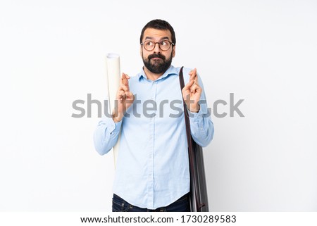 Young architect man with beard over isolated white background with fingers crossing and wishing the best