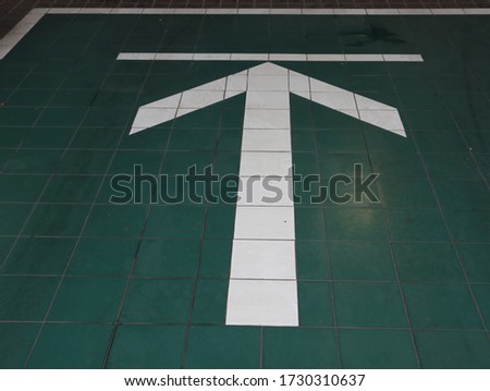 The white arrow shows the straight direction on the green ceramic tile.