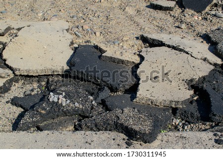 Pieces of broken asphalt. Black plates, gravel. Concept of earthquake, destruction, roadwork.