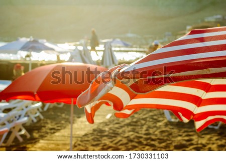 Black Sea Crimea bay Sudak beach sunset red and white umbrellas background Royalty-Free Stock Photo #1730331103