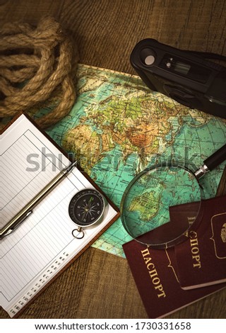Preparing for an adventure trip. At night, inspection of an old map with a compass and a magnifier under the light of a lamp. Dark background.