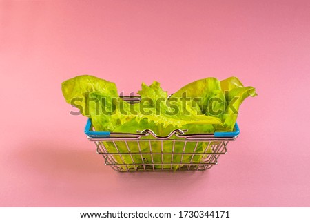 fresh salad in a grocery basket on a pink background. nutritious food. vegetarian products. place for the inscription.
