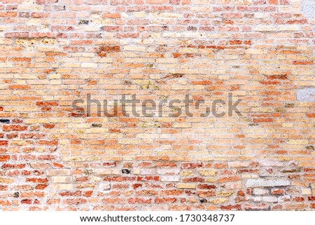 An old weathered brick wall with red bricks as a background