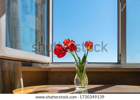 A bouquet of tulips on a windowsill by an open window.