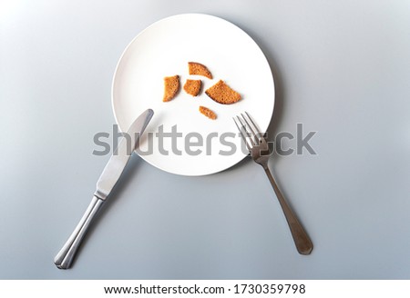 White plate with some crackers, knife and fork, poverty, bankruptcy, hunger, concept picture