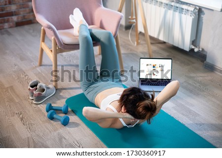 oung sporty slim woman has internet video online fitness training instructor modern laptop screen. Healthy lifestyle concept, online fitness and sport lessons. Pumping press Royalty-Free Stock Photo #1730360917
