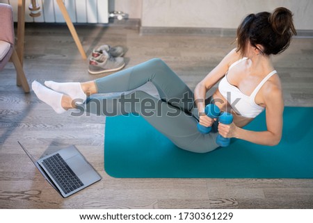 oung sporty slim woman has internet video online fitness training instructor modern laptop screen. Healthy lifestyle concept, online fitness and sport lessons. Pumping press Royalty-Free Stock Photo #1730361229