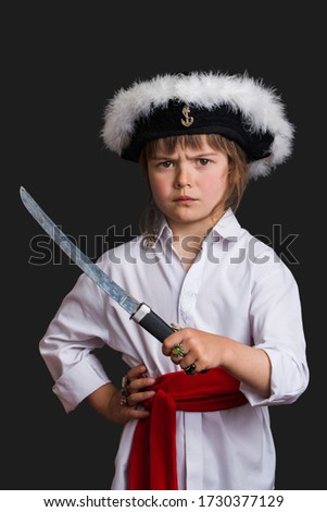 Little funny girl plays a serious evil formidable pirate captain  isolated on a dark gray background.