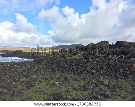 Photo of several overturned Moais located in an archaeological site on the rocky coast of Easter Island, Chile.